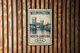 A metal sign with a drawing of a bridge and the text "WILMINGTON NORTH CAROLINA U.S.A."