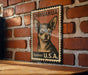 A framed poster of a Chihuahua dog is displayed on a brick wall, with the text "CHIHUAHUA forever U.S.A." printed on it.