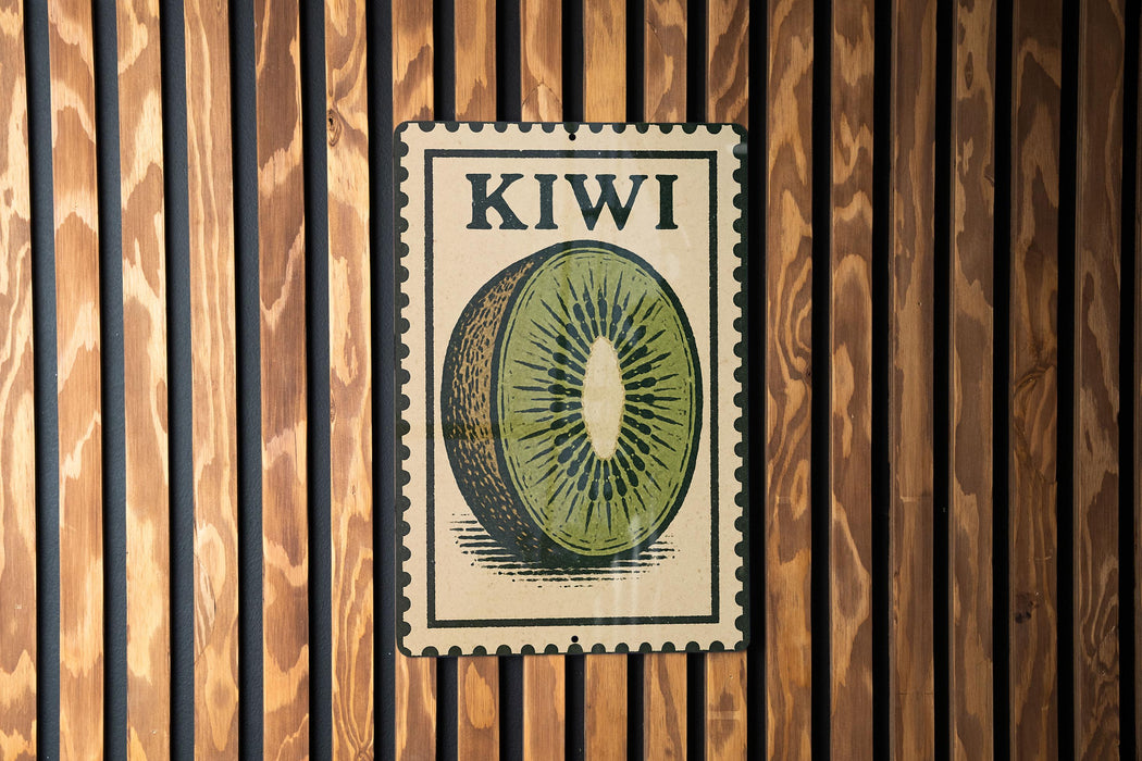 A vintage-style metal sign with the word "KIWI" printed on it, featuring a close-up illustration of a kiwi fruit slice.