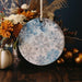 a blue and white snowflake ornament next to a vase of flowers