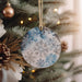 a blue and white snowflake ornament hanging from a christmas tree