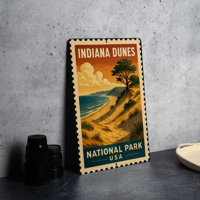 A vintage-style metal sign for Indiana Dunes National Park, featuring an illustration of a scenic landscape with a tree and a beach.