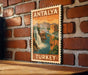 A vintage postage stamp depicting a waterfall and mountains, with the text "ANTALYA TURKEY" printed on it, is displayed on a brick wall.