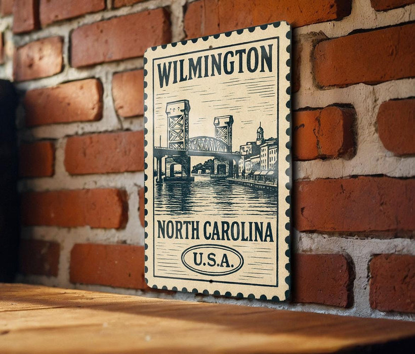 A vintage-style postage stamp featuring the Wilmington Bridge in North Carolina, United States, hanging on a brick wall.