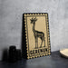 a decorative metal plaque with a black and white illustration of a gazelle, and the word "Gerenuk" written below it.