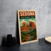 A vintage-style metal sign with the text "SEDONA ARIZONA USA" and an illustration of the iconic rock formations of Sedona, Arizona.
