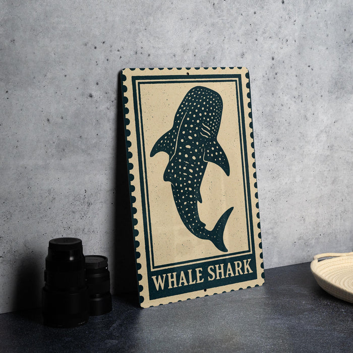 a framed artwork of a whale shark, which is a large shark species, placed on a table next to some black camera lenses.