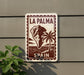 a sign that reads "LA PALMA" and "SPAIN", with a palm tree and a mountain in the background.