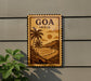 A wooden sign with a tropical beach scene and palm trees, mounted on a wall.