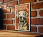 A vintage-style metal sign featuring a Labrador Retriever dog, mounted on a brick wall.
