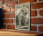 A wooden table with a framed illustration of a walrus on it, mounted on a brick wall.