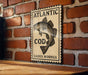 A sign with the text "ATLANTIC COD GADUS MORHUA" and an illustration of a fish is displayed on a brick wall.