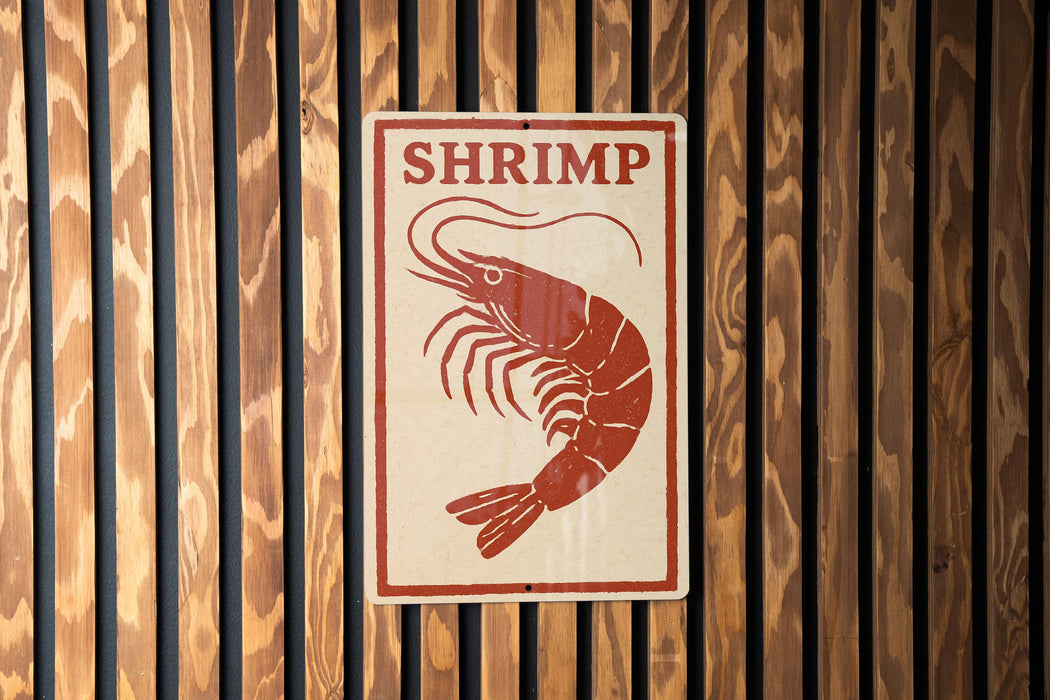 A sign with the word "SHRIMP" written on it, depicting a shrimp.