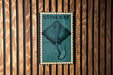 A metal sign with a blue background and a graphic of a stingray is mounted on a wooden wall.