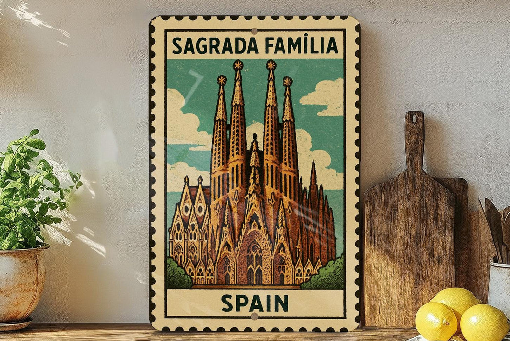 A vintage-style metal sign with the text "Sagrada Familia" and "SPAIN" printed on it, featuring an illustration of the Sagrada Familia church in Barcelona, Spain.