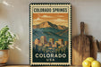 A vintage-style metal sign with a mountain landscape and a cityscape, featuring the text "COLORADO SPRINGS USA" and "COLORADO" at the top and bottom.