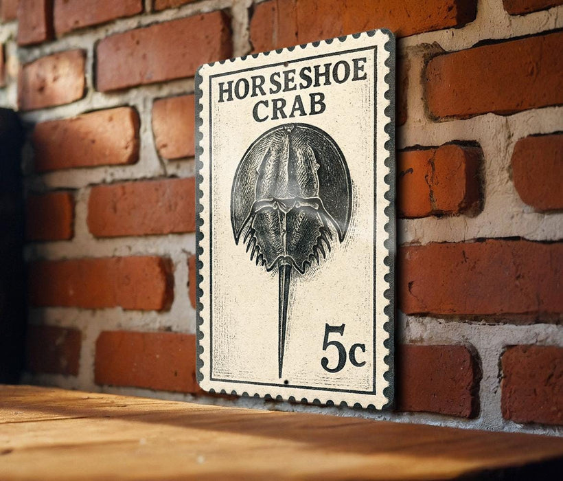 A black and white postage stamp featuring a detailed illustration of a horseshoe crab, mounted on a brick wall.