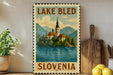 A vintage-style metal sign depicting Lake Bled in Slovenia, with a church spire and mountains in the background.
