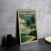 A vintage-style metal stamp depicting a tropical beach scene with palm trees and a calm ocean, placed on a gray surface next to some black camera lenses.