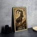 A metal stamp featuring an illustration of a goat with curved horns, placed on a table next to some black camera lenses.