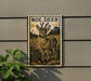 a decorative plaque with a roe deer illustration on it, mounted on a wall next to a plant.