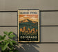 A vintage-style metal sign with a mountain landscape and a cityscape, mounted on a wall.