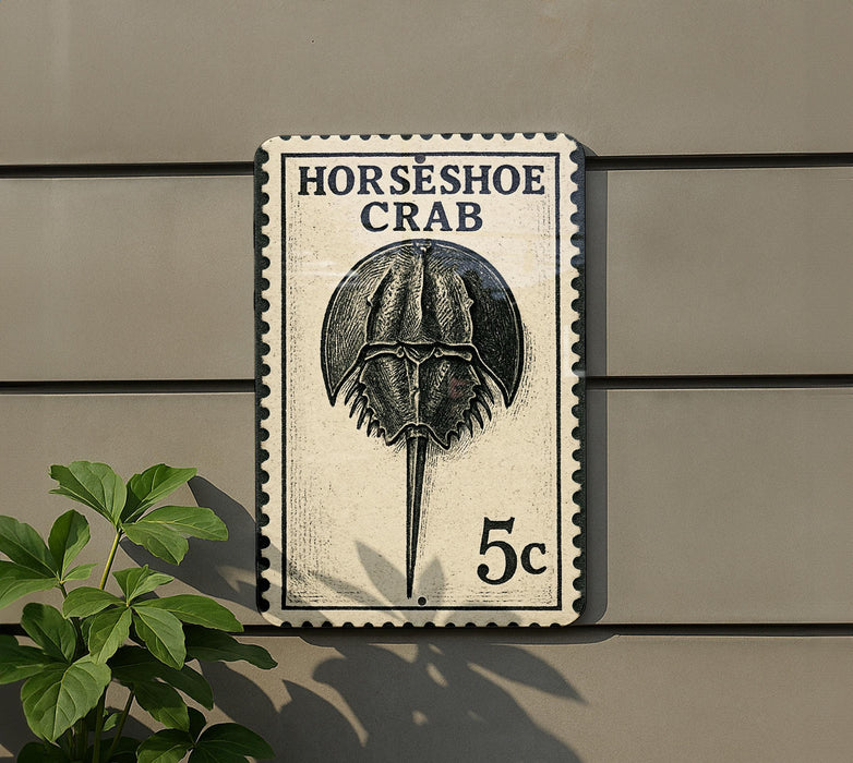 A postage stamp featuring a horseshoe crab, mounted on a wall next to a plant.
