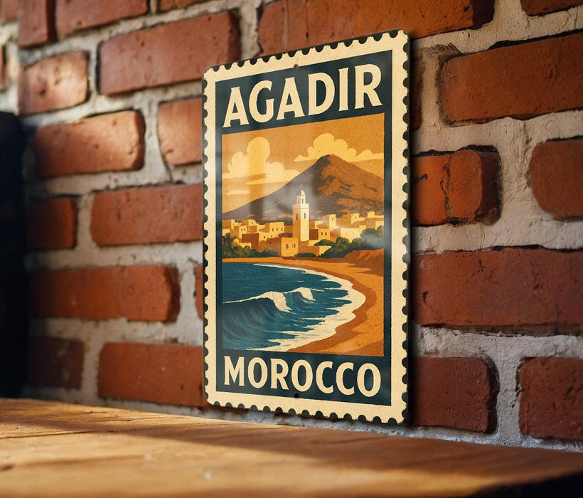 A vintage-style stamp depicting a coastal cityscape with mountains in the background, hanging on a brick wall.