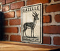a sign with a black and white illustration of a gazelle, mounted on a brick wall.