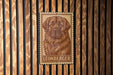 A metal sign featuring a large illustration of a dog's face, with the word "LEONBERGER" written below it, is mounted on a wooden wall.