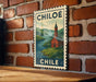 A framed poster of a church and a river is hanging on a brick wall.