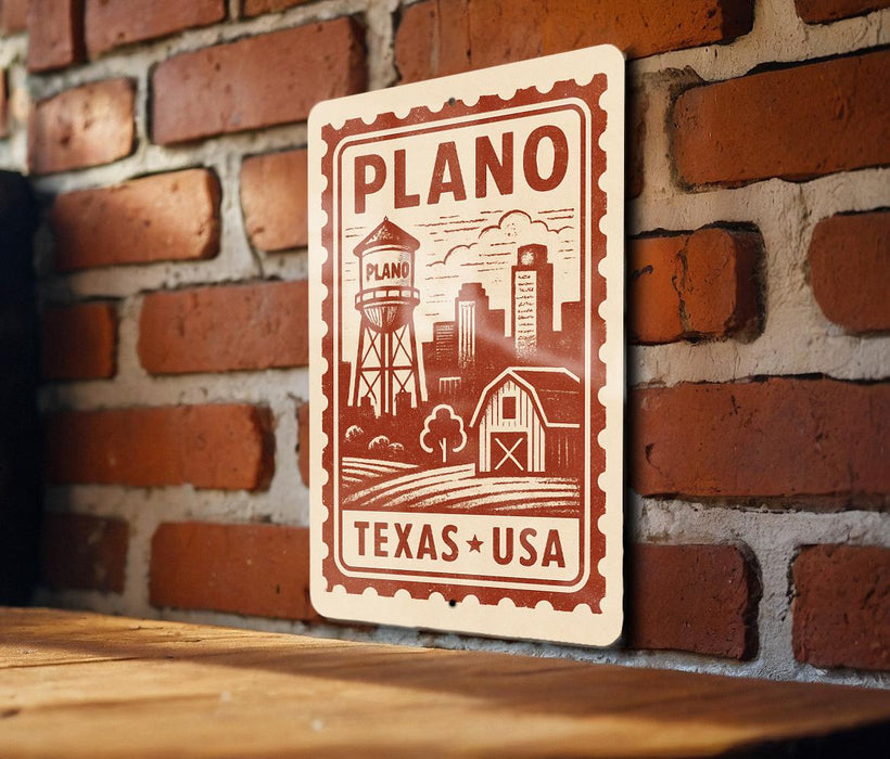 A sign with the text "PLANO TEXAS USA" and an illustration of a water tower and barn, mounted on a brick wall.