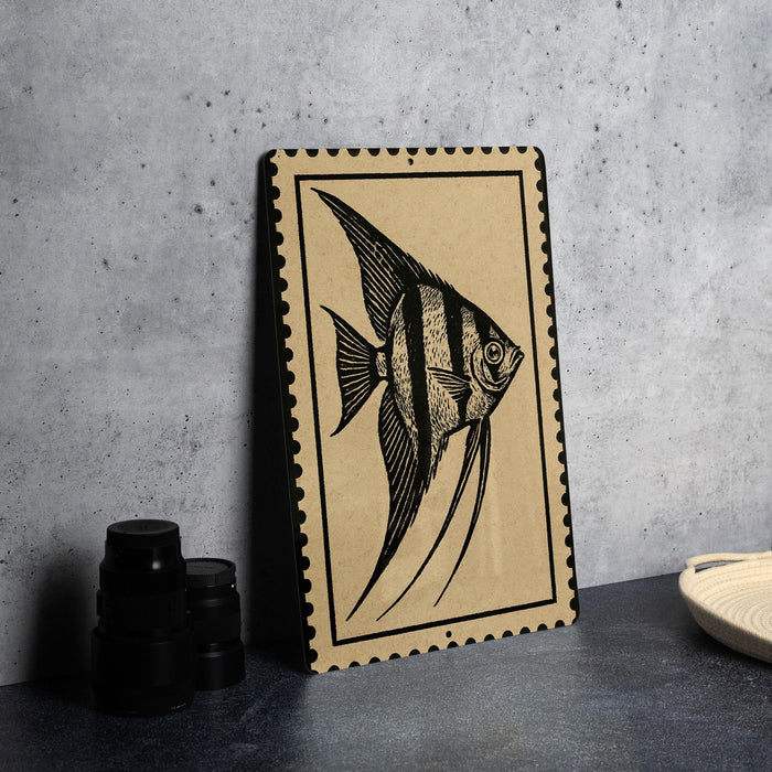 a framed artwork of an orangish fish, which is placed on a table next to some black camera lenses.