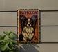 A Papillon dog is depicted on a postage stamp-like sign, mounted on a wall.