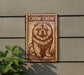 a sign with a chow chow dog illustration on it, mounted on a wall next to a plant.