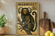 a framed illustration of a marmoset monkey, a type of primate, sitting on a branch. The frame has a stamp-like border and the word "MARMO set" is written on it. The monkey is depicted in a detailed and realistic manner, with its distinctive facial features and fur. The image is displayed on a shelf, with a potted plant and a wooden cutting board visible in the background.