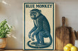 a blue monkey sitting on a wooden surface, with a potted plant to the left and a wooden cutting board to the right.