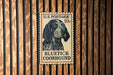 A U.S. postage stamp featuring a blue and black illustration of a blue and black dog, specifically a blue and black Coonhound, mounted on a wooden wall.