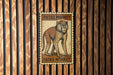 A wooden wall with a framed illustration of a monkey, which appears to be a postage stamp or sign.