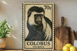 A vintage-style stamp depicting a colobus monkey, with the text "COLBUS COLOBUS" printed on it. The stamp is placed on a shelf next to a wooden cutting board and a potted plant.