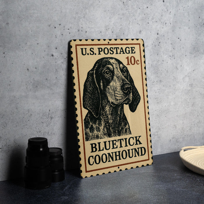 A U.S. postage stamp featuring a blue and black illustration of a blue and black dog, specifically a blue and black conhound, is displayed on a table.