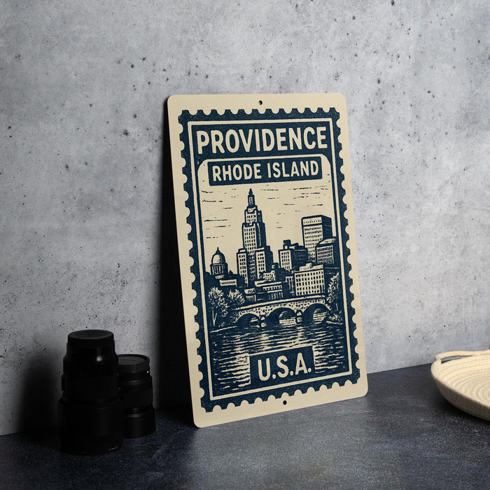 A metal sign with a cityscape illustration and text, placed on a table next to some black camera lenses.