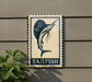 a sign with a blue and white design depicting a sailfish, mounted on a wall.