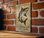 A wooden table with a framed image of a tiger shark on it, mounted on a brick wall.