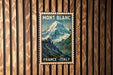A vintage-style poster of a mountain landscape with the text "MONT BLANC FRANCE ITALY" displayed prominently in the center.