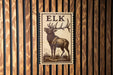 A wooden wall with a framed image of a deer, which appears to be a postage stamp or a decorative piece.