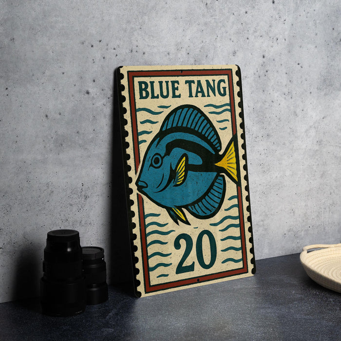 A framed poster of a blue tang fish, with the number 20, is displayed on a table next to some black camera lenses.