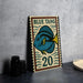 A framed poster of a blue tang fish, with the number 20, is displayed on a table next to some black camera lenses.