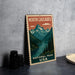 A vintage-style metal sign for North Cascades National Park in the United States, featuring a mountain landscape with a river and pine trees.