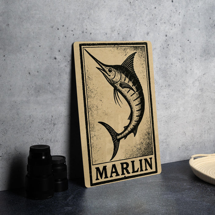 a wooden sign with a black and white illustration of a marlin fish, placed on a gray countertop next to some black camera lenses.